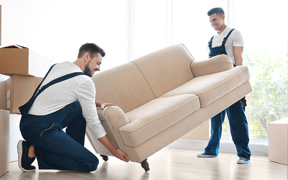 Zwei Männer bringen ein Sofa in ein Zimmer in der neuen Wohnung